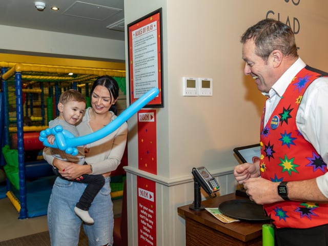 Theodore Legg (1) with mum Paige Curtis (28) excited to receive a balloon creation from magician Roy Charles. Picture: Mike Cooter (040323)