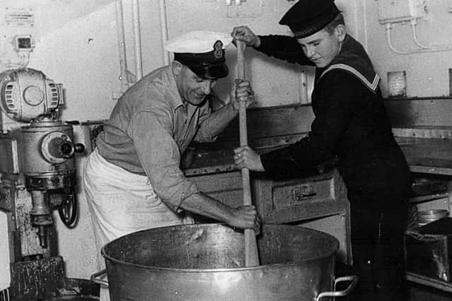 Chief Petty Officer Les Russell and youngest sailor Jerry Locke stirring the Christmas pudding mix in 1949 aboard HMS Theseus, a light aircraft carrier.