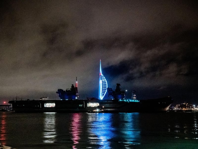 HMS Queen Elizabeth sailing past the Spinnaker Tower illuminated in colours for Elin Martin.