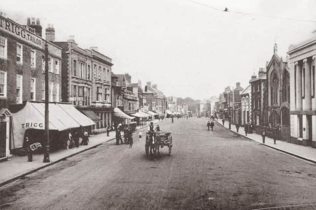 A horse drawn cart passes Trigg the tailors in West Street, Fareham. Undated