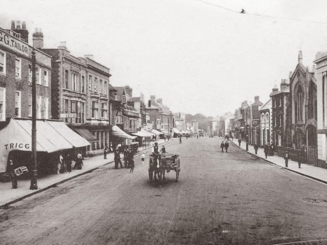 A horse drawn cart passes Trigg the tailors in West Street, Fareham. Undated