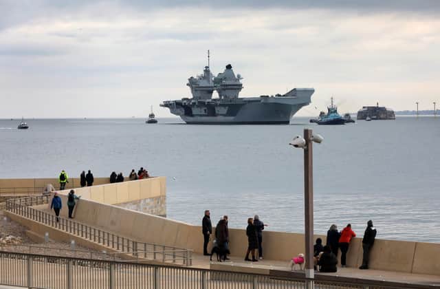HMS Queen Elizabeth approaches the newly reopened walkway on the sea defences at Long Curtain Moat