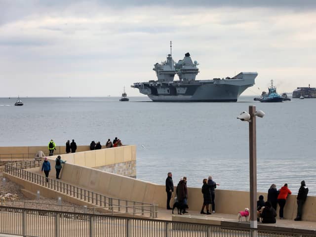 HMS Queen Elizabeth approaches the newly reopened walkway on the sea defences at Long Curtain Moat
