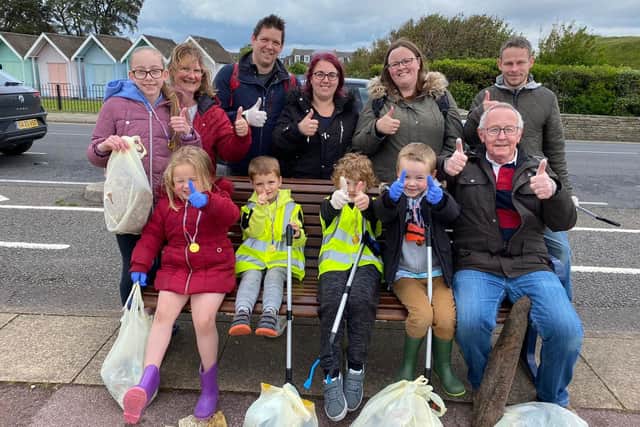 Eleanor (left of bottom row in red jacket) and mum Claire (second from right on top row) with their fellow beach clean volunteers
