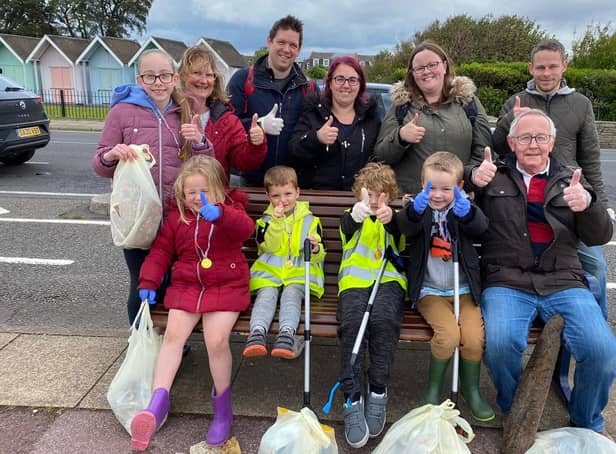 Eleanor (left of bottom row in red jacket) and mum Claire (second from right on top row) with their fellow beach clean volunteers