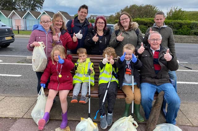 Eleanor (left of bottom row in red jacket) and mum Claire (second from right on top row) with their fellow beach clean volunteers