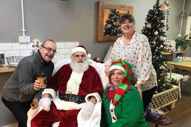 The Rotary Club Fareham celebrate Christmas by giving all children the chance to meet Santa at Coco’s Coffee Shop. 
Pictured: Coco’s coffee shop in Miller Drive Fareham with customer Kevin Wickham, Santa, Rotarian and coffee shop owner Jackie Avis standing and elf Belle Johnson kneeling.