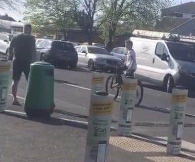 One of the two boys filmed abusing Gosport Asda staff members, Charlie Baldwin, is pictured riding away from the store and being followed by a member of the public. Charlie was today forced to head back to the shop by his father to apologise.