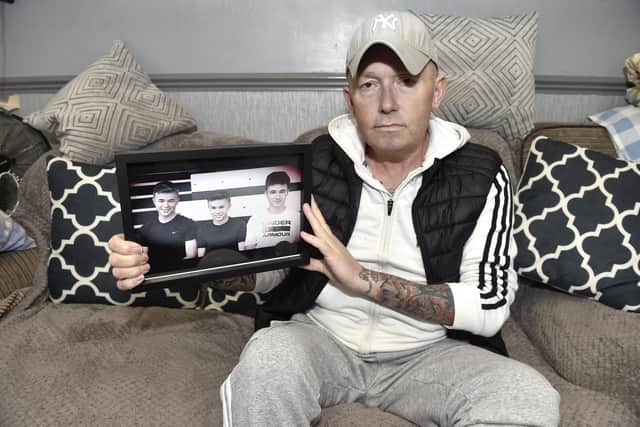 Iain Smith with a picture of three out of his four boys from left, Rocky, Harry and Jay Picture: Sarah Standing (270423-2612)