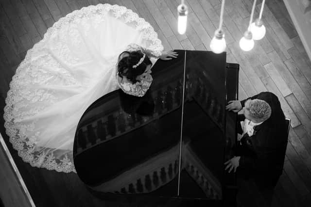 Jemma and Luke Wainwright posing at a grand piano.
Picture: Carla Mortimer Wedding Photography.