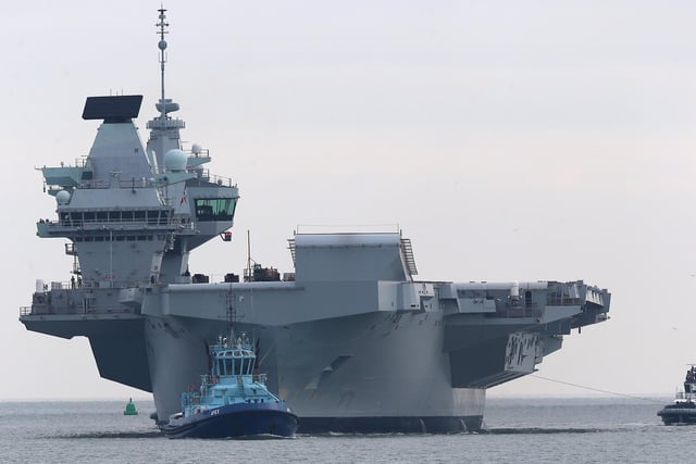 HMS Queen Elizabeth approaches the newly reopened walkway on the sea defences at Long Curtain Moat, as she returns to Portsmouth Naval Base