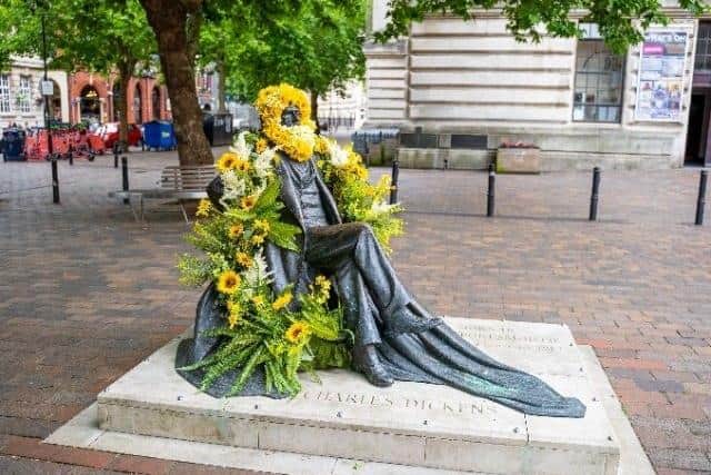 The Charles Dickens statue in Guildhall Square has been covered in flowers.