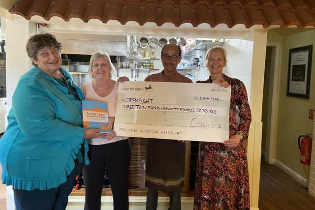 (LtoR) Blind cook Penny hands Carol her book and chef patron Lauro presents Open Sight Chair, Sue, with the donation cheque.