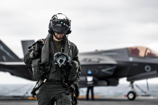 A British F-35B Lightning jet pilot walks across HMS Queen Elizabeth's flight deck with his fighter jet in the background. This image was part of the Peregrine Trophy winning selection from HMS Queen Elizabeth. By Leading Photographer Dan Shepherd