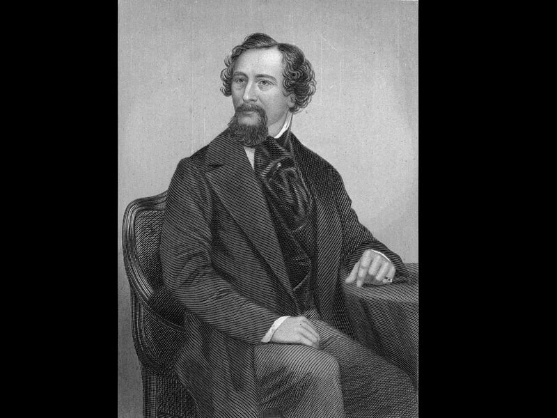 Portrait of British author Charles Dickens (1812 - 1870) as he sits at a table, mid 1800s. He wears a jacket and tie, as welll as a ring on his left hand. (Engraving by Robert Whitechurch/Hulton Archive/Getty Images)