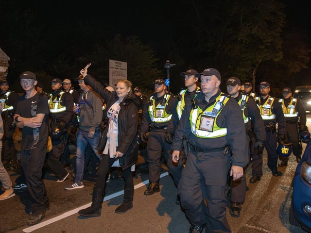 Over 100 illegal migrants aboard two RNLI lifeboats entered Portsmouth Harbour, arriving at Fort Blockhouse in Gosport, Hampshire on Sunday evening. Pictured just after midnight are dozens of police on Clayhall road in Gosport moving a large group of protesters before the buses leave Credit: pictureexclusive.com