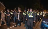 Over 100 illegal migrants aboard two RNLI lifeboats entered Portsmouth Harbour, arriving at Fort Blockhouse in Gosport, Hampshire on Sunday evening. Pictured just after midnight are dozens of police on Clayhall road in Gosport moving a large group of protesters before the buses leave Credit: pictureexclusive.com