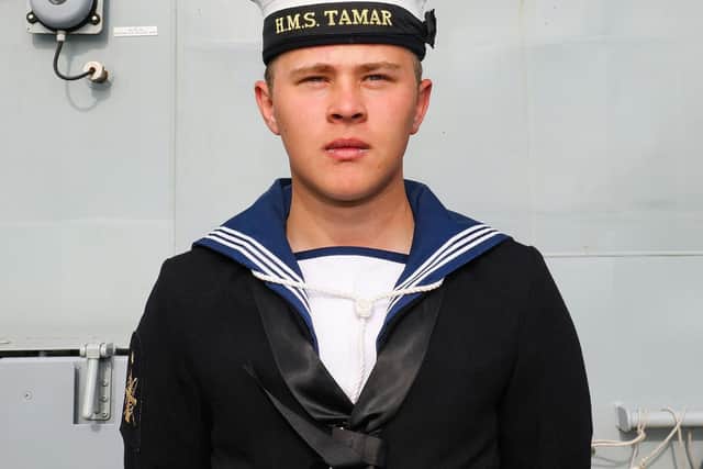 One of HMS Tamar's sailors stood next to the ship's name plaque. Photo: LPhot Alex Ceolin.