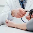 Doctor checking blood pressure of a patient, he is measuring pulses with a sphygmomanometer, hands close up. Photo: Adobe - for illustrative purposes