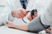 Doctor checking blood pressure of a patient, he is measuring pulses with a sphygmomanometer, hands close up. Photo: Adobe - for illustrative purposes