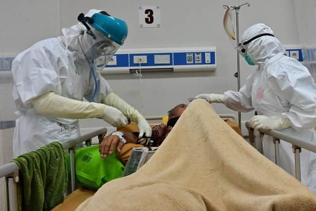 Nurses tend to a coronavirus patient. Stock Photo by ADEK BERRY/AFP via Getty Images)