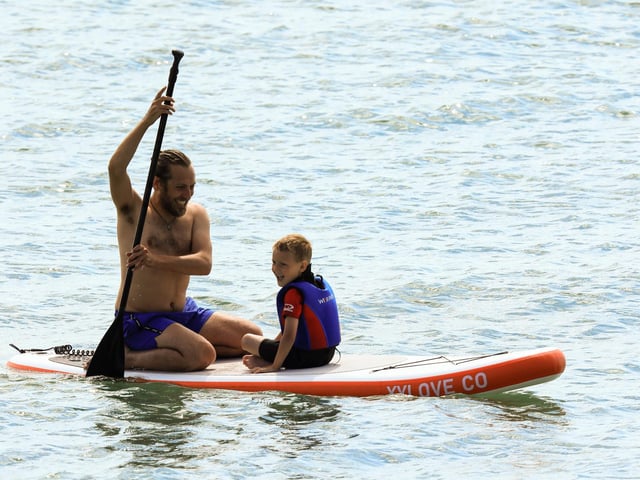 A pair enjoying a laugh on a paddle-board during the hot weather weekend.