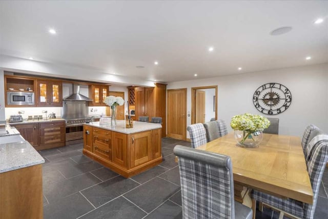 The kitchen has solid wood base and wall units with granite worktops, and high-end integrated appliances, including two dishwashers, fridge, freezer, and stainless-steel range cooker with extractor hood.