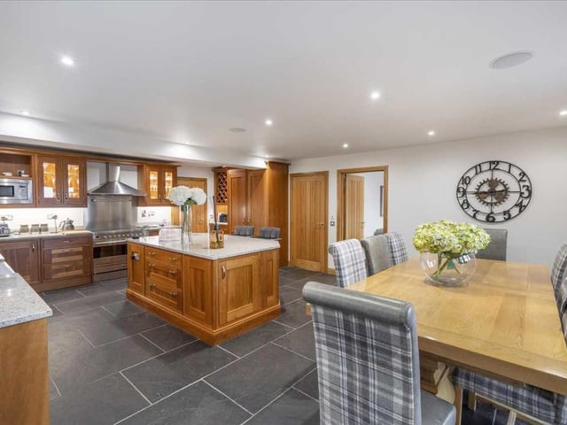 The kitchen has solid wood base and wall units with granite worktops, and high-end integrated appliances, including two dishwashers, fridge, freezer, and stainless-steel range cooker with extractor hood.