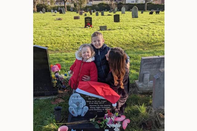 Kat Eastman who is doing a fundraiser for QA's bereavement suite as it marks 10 years since she gave birth to her stillborn daughter Ruby.
Pictured is: Kat Eastman with Rebecca and Declan at Ruby's grave.