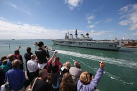 Relatives of navy personnel wave as the helicopter carrier HMS Illustrious departs Portsmouth for a deployment to the Mediterranean on August 12, 2013 in Portsmouth. Photo by Oli Scarff/Getty Images