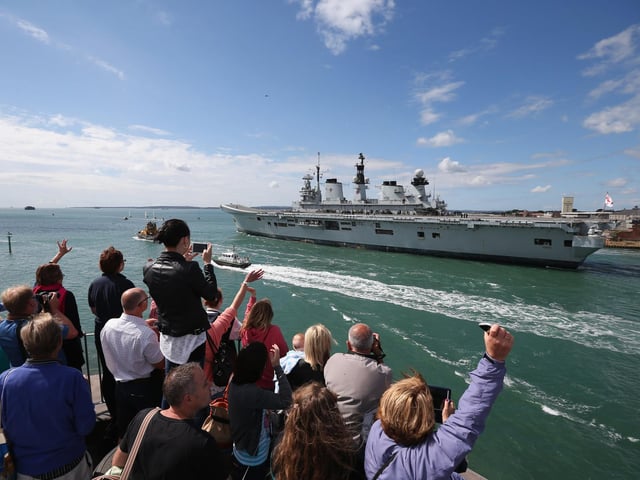Relatives of navy personnel wave as the helicopter carrier HMS Illustrious departs Portsmouth for a deployment to the Mediterranean on August 12, 2013 in Portsmouth. Photo by Oli Scarff/Getty Images