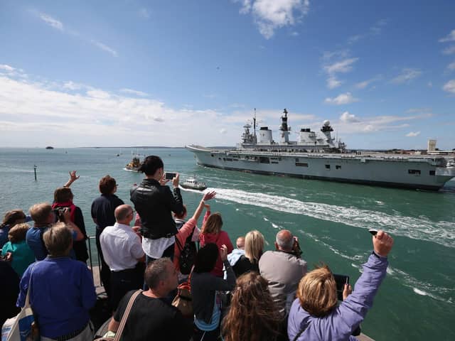 Relatives of navy personnel wave as the helicopter carrier HMS Illustrious departs Portsmouth for a deployment to the Mediterranean on August 12, 2013 in Portsmouth. Photo by Oli Scarff/Getty Images