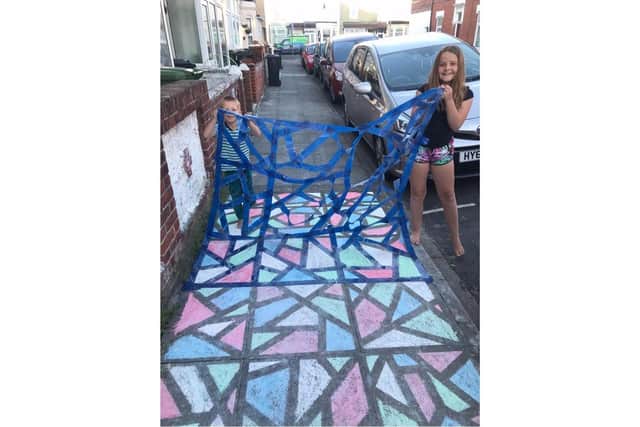 Chloe and Callum Topham, 10 and 5, have brightened up Portchester Road in North End with their colourful chalk design. Pictured: The pair pulling up the tape from their artwork