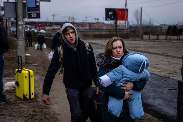 A woman carries her child as they flee Irpin, Ukraine.