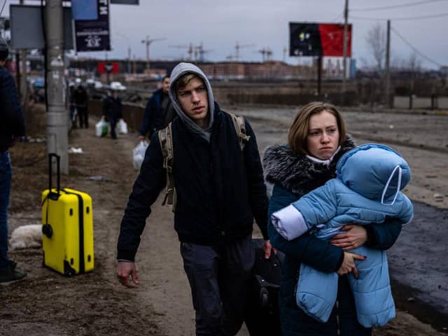 A woman carries her child as they flee Irpin, Ukraine.