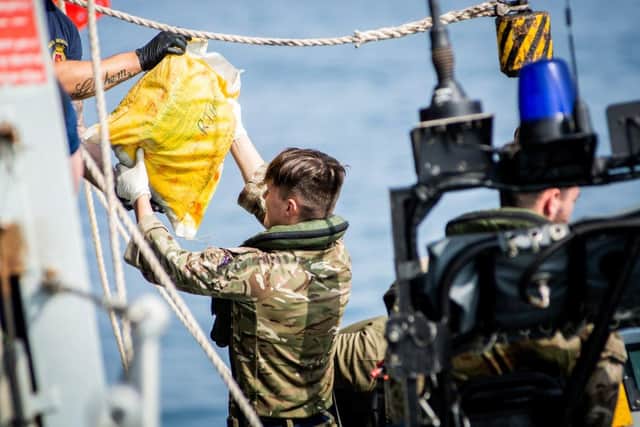 A Royal Marine hands a sailor on HMS Montrose a sack of hashish
Picture: Royal Navy
