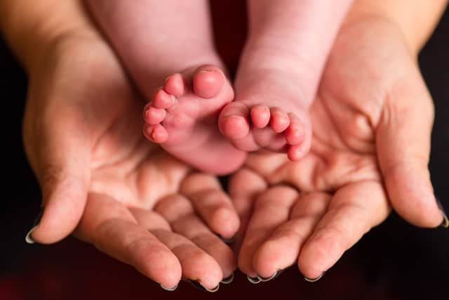 A mother holding the feet of a new baby. Photo: PA