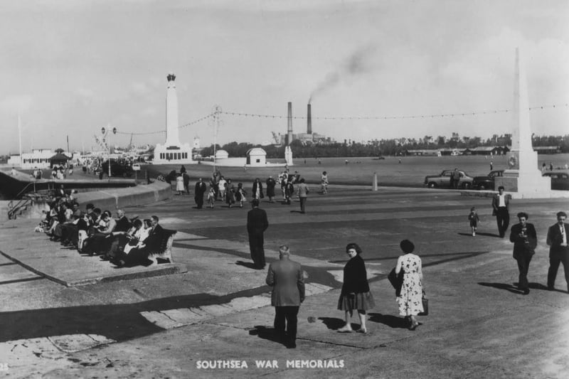Men in suits women in coats, it must be the late 1950s or early 1960s  along the seafront. Notice the power station chimneys.