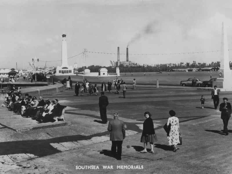 Men in suits women in coats, it must be the late 1950s or early 1960s  along the seafront. Notice the power station chimneys.