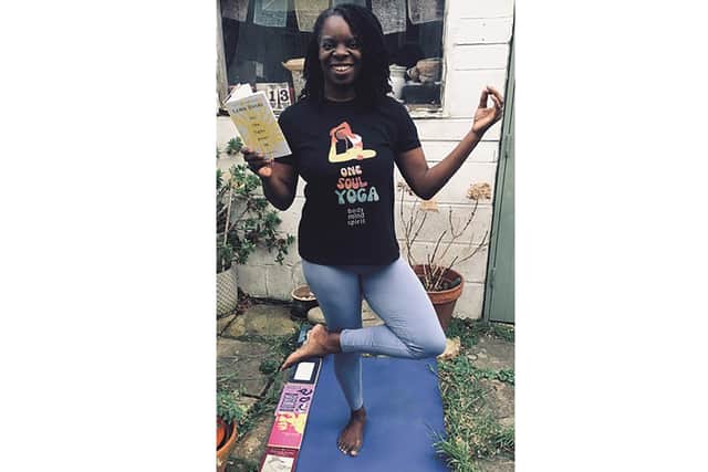 Yoga teacher Andrea Bailey in a tree pose with Lemn Sissay's latest collection of poetry Let The Light Pour In