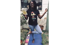 Yoga teacher Andrea Bailey in a tree pose with Lemn Sissay's latest collection of poetry Let The Light Pour In