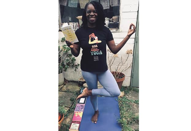 Yoga teacher Andrea Bailey in a tree pose with Lemn Sissay's latest collection of poetry Let The Light Pour In