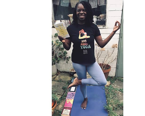 Yoga teacher Andrea Bailey in a tree pose with Lemn Sissay's latest collection of poetry Let The Light Pour In