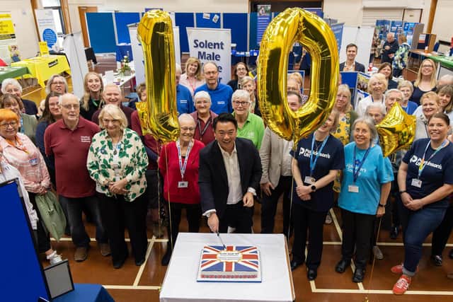 Alan Mak MP cuts the special anniversary cake surrounded by exhibitors at his 10th annual Havant Constituency Community Information Fair
