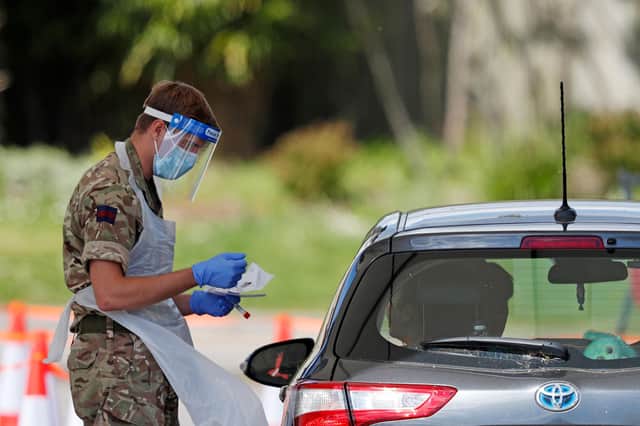 A member of the armed forces takes a swab to test for the novel coronavirus COVID-19 from a visitor to a drive-in testing facility at the Chessington World of Adventures Resort, in Chessington, southwest of London, in May. Picture: Adrian Dennis/Getty Images