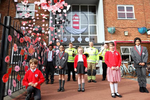 School children, from left, Maks Sikarjov, 8, Robson Yusef, 10, Fatima Hassawi, 9, Bella-Mae Mills, 6, Brooke Tappenden, 8, and Fri Achiri, 9, with firefighters, rear, left to right, firefighter Nico Razzell, firefighter Bill Cutler and crew manager Jamie Kelly with the children's Remembrance poppy installation at Ark Ayrton Priamry Academy, Somers Road, Southsea. The fire service helped with the installation work at the schoolPicture: Chris Moorhouse   (jpns 101121-)