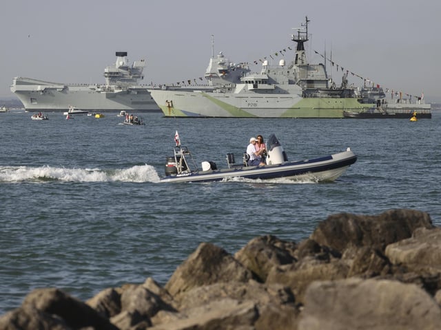 Pictured: HMS Queen Elizabeth enters the Solent off of Cowes passing HMS Tyne and conducts a gun salute in front of the Royal Yacht Squadron.