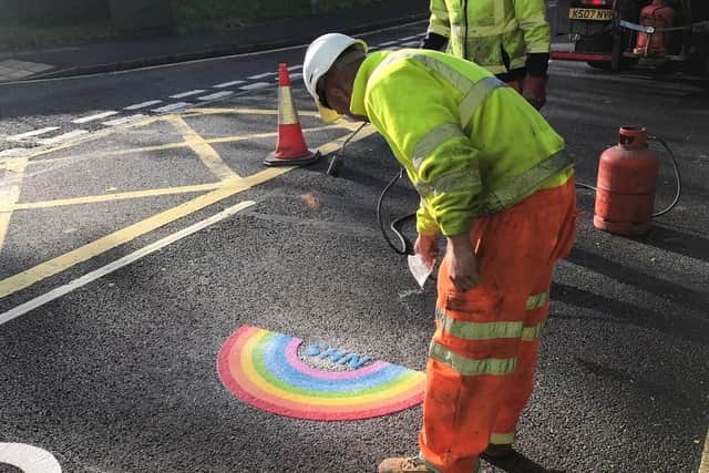 Road workers add a 'thermoplastic' rainbow to the message of thanks.