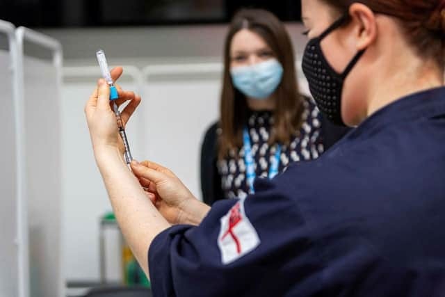 Leading Naval Nurse Megan Muirhead learns the vaccination procedure from an NHS vaccination trainer.