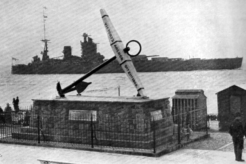 A beautifully posed photograph of the battleship HMS Nelson passing HMS Victory’s anchor.